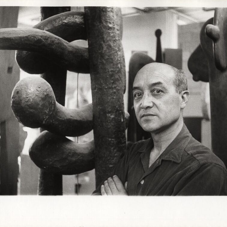 Portrait of artist and designer Isamu Noguchi standing next to one of his sculptures, The Isamu Noguchi Foundation and Garden Museum, New York